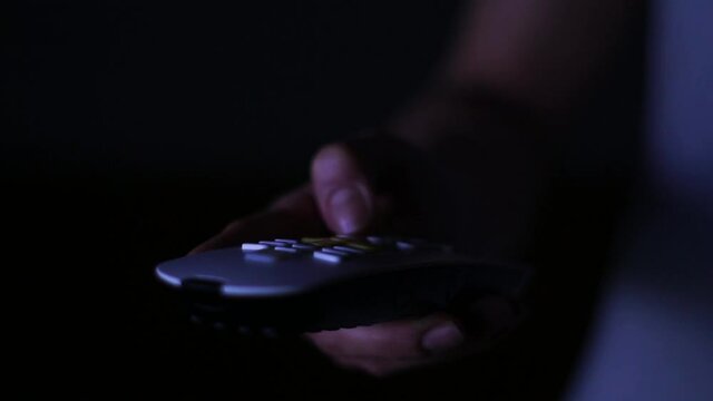 Hand holding a tv remote control, changing tv channels