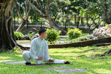 Young man practicing traditional Tai Chi Chuan, Tai Ji and Qi gong in the park for healthy,...