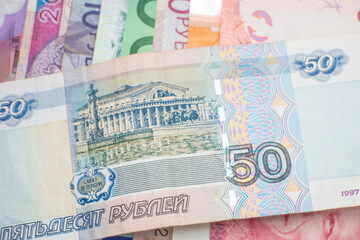 A Russian Ruble banknote arranged over a rainbow of banknotes of different world currencies, including Euro notes, Australian Dollars, Israeli Shekels, South African Rand and Polish Złoty. 