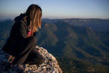 Naklejka premium Young woman on the top of a mountain staring at the horizon. Concept of lifestyle and nature. Long shot.