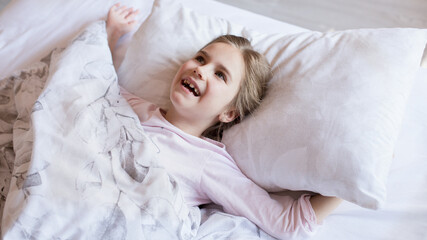 Obraz na płótnie Canvas Cute little girl in bed woke up in the morning