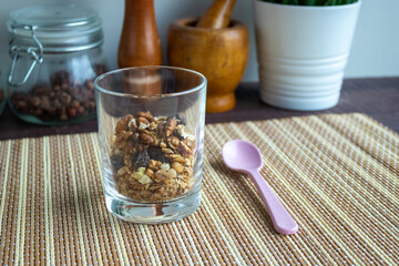 Useful muesli with nuts in a glass and a spoon on a wooden table. Healthy lifestyle