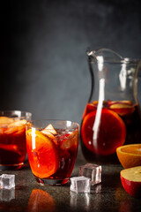 Refreshing red wine sangria or punch with fresh fruits in glasses and pincher on black background