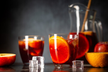 Refreshing red wine sangria or punch with fresh fruits in glasses and pincher on black background