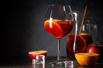 Refreshing red wine sangria or punch with fresh fruits in glasses and pincher on black background