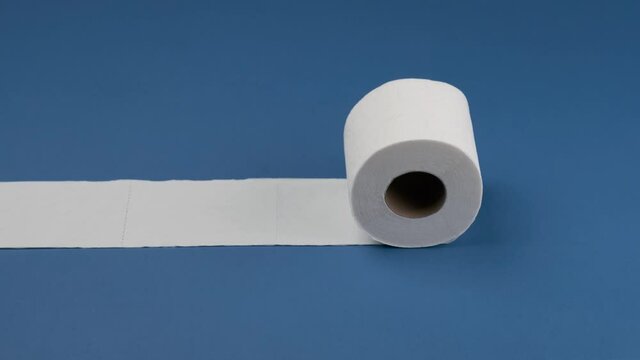 Toilet paper rolls and stops horizontally on a blue background.