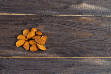 Almonds scattered on a dark table. Copyspace, flatlay on wood background.