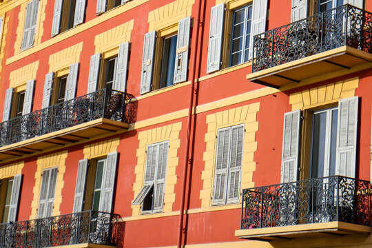 Typically colorful orange facade of Provencal buildings with small metal balconies and colorful shutters, seen in Nice, French Riviera, southern France. 