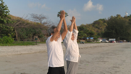 Family concept. Old people doing yoga on the beach together.