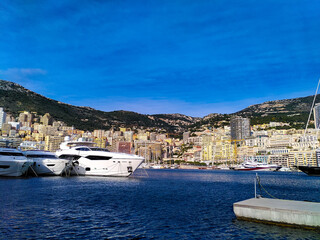 Fototapeta na wymiar Skyline of Monte Carlo with luxury yachts anchored in the harbor on a sunny day. Monaco-Ville, Monaco. 