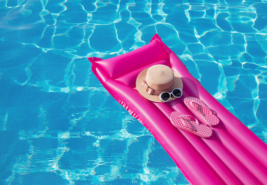 Beach summer holiday background. Inflatable air mattress, flip flops and hat on swimming pool.