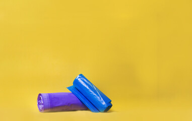 Colored garbage bags on yellow background. Minimalistic composition. Copy space