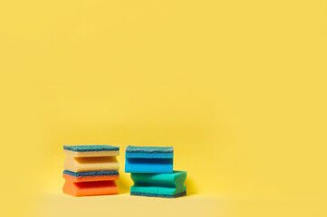 Colored sponges for washing dishes on yellow background. Minimalistic composition