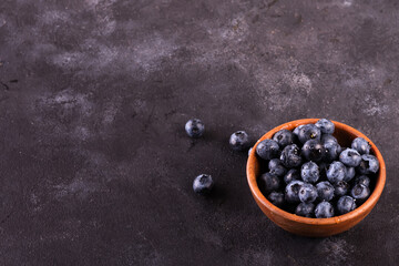 Blueberries in a bowl on a stone table.