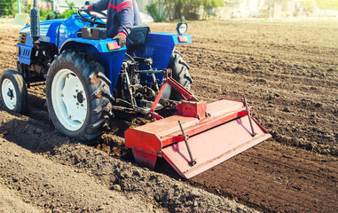 Farmer on a tractor cultivates land after harvesting. Grinding loosening plowing crumbling soil for...
