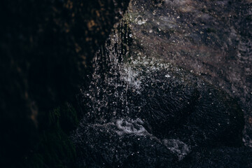 A small natural waterfall. Waterfall in the grotto in the national park. Grotto with water