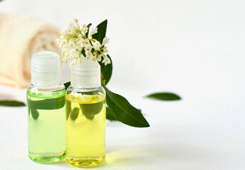 Two bottles with a cosmetic product and a towel with flowers in the background without focus. Spa background with place for text.