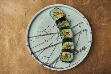 Classic japanese sushi rolls - rolls with salmon, cucumber, shiitake and lettuce on a white plate on a copper, metal background