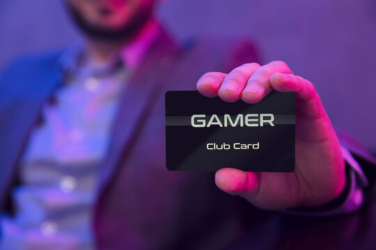 Man's hand holds gamer clubcard. Gentleman in suit holds gamer membership club card in his hand