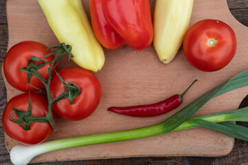 Onions are on the cutting board, hot and sweet peppers and red tomatoes..