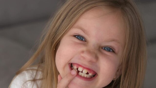 Adorable little toothless girl laughing happily, close-up portrait. Cheerful childhood, beautiful young face, preschool age. High quality 4k footage