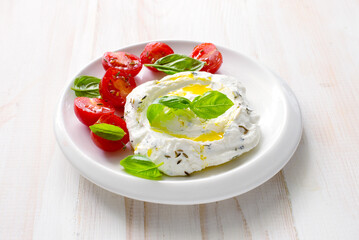 Homemade cream cheese ( labneh) wiht cherry tomatoes, basil and olive oil close up