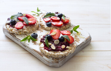Open sandwiches with cream cheese, strawberries, blueberries, jam and almond flakes close up