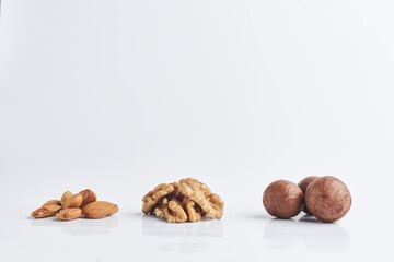 almonds, walnuts, macadamia on a white background. a few handfuls of raw nuts. copy space for text.