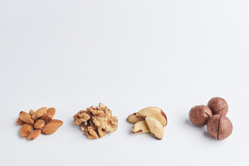 almonds, walnuts, macadamia, Brazilian nut on a white background. a few handfuls of raw nuts. copy space for text.