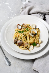 pasta with clams and parsley italian Spaghetti alle Vongole in white plates on a grey background. recipe food seafood.  top view