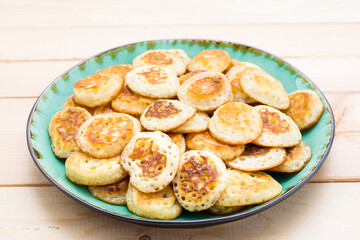 Trend breakfast. Dutch mini pancakes on plate on a wooden table. Close-up