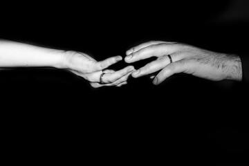 man and woman reach out to each other with their hands out of the darkness