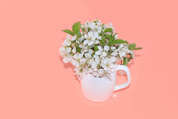 Abstract floral arrangement, flowering cherry branches in a mug, place for text. Creative modern bouquet, minimal holiday concept. Flower card, spring banner