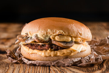 homemade burger with mushrooms in rustic style on wooden background