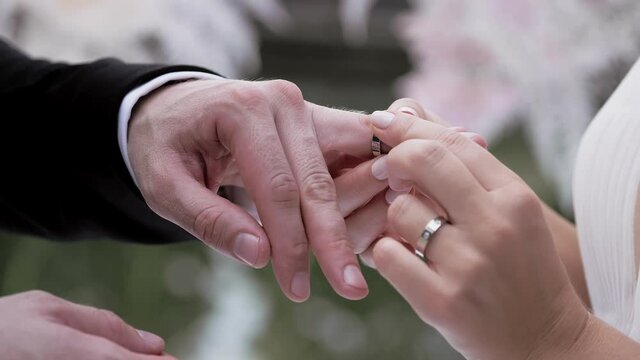 Bride putting wedding ring on brides finger close up summer day no face slow. luxury lifestyle. Bridal fashion.