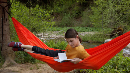 Relaxed woman reading book in hammock outdoor. Chilling at the nature. 