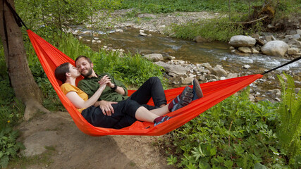 Loving couple lying in hammock at the nature enjoying life together. Spending good time at the nature.