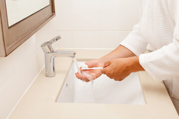 Man in bathrobe brush teeth in bathroom