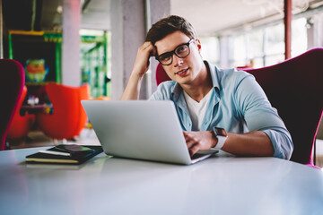 Pensive student reading information from web pages on laptop computer