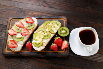 Tasty homemade fruit bruschetta with chopped strawberries, ricotta and kiwi, healthy and delicious dessert, snacks, antipasti