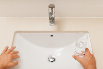 man arms closeup with glass water in bathroom