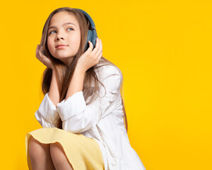 Girl with headphones. Beautiful European teen girl 10 years old listening to music with headphones,...