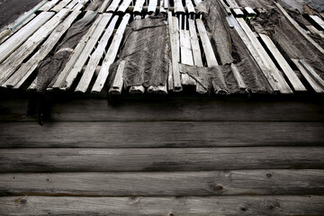 Background with an old house with a leaky roof and gray logs