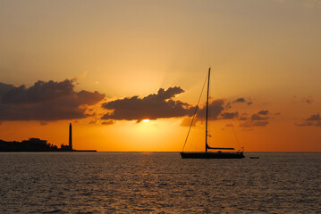 Sailing yacht and Lighthouse in the sun rays early in the morning