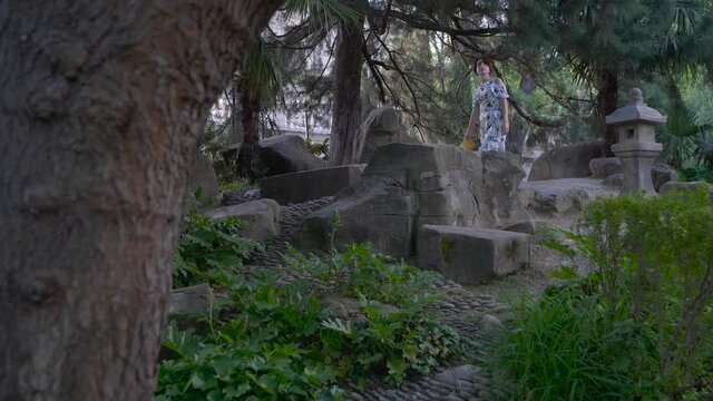 girl in the park lays a book on a stone
