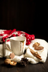 Obraz na płótnie Canvas White cup with tea, knitted scarf and nuts near, on wood background