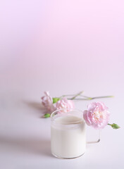 Fototapeta na wymiar glass of milk on white table with soft pink flowers. elegant pink carnation flowers in pastel colours
