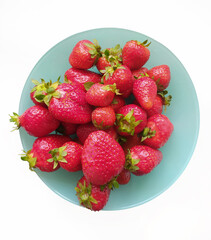 Strawberries in a turquoise bowl, top view, isolated on white background