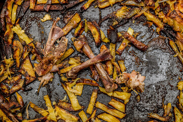 Fried burnt potatoes and chicken bones on a baking sheet in high resolution.
