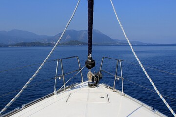 The bow of a sailboat sailing in a calm blue sea